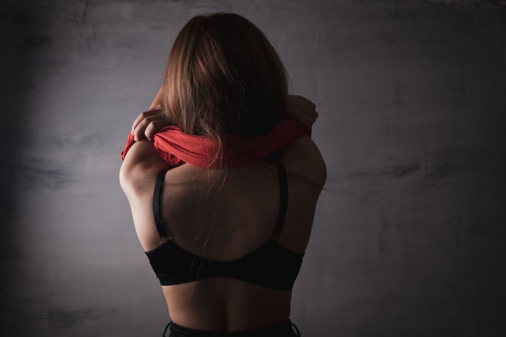 Woman in black bra removing red shirt
